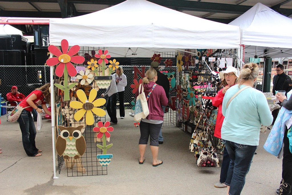 Colorful wooden flower and owl art vendor booth at an outdoor Haymarket market