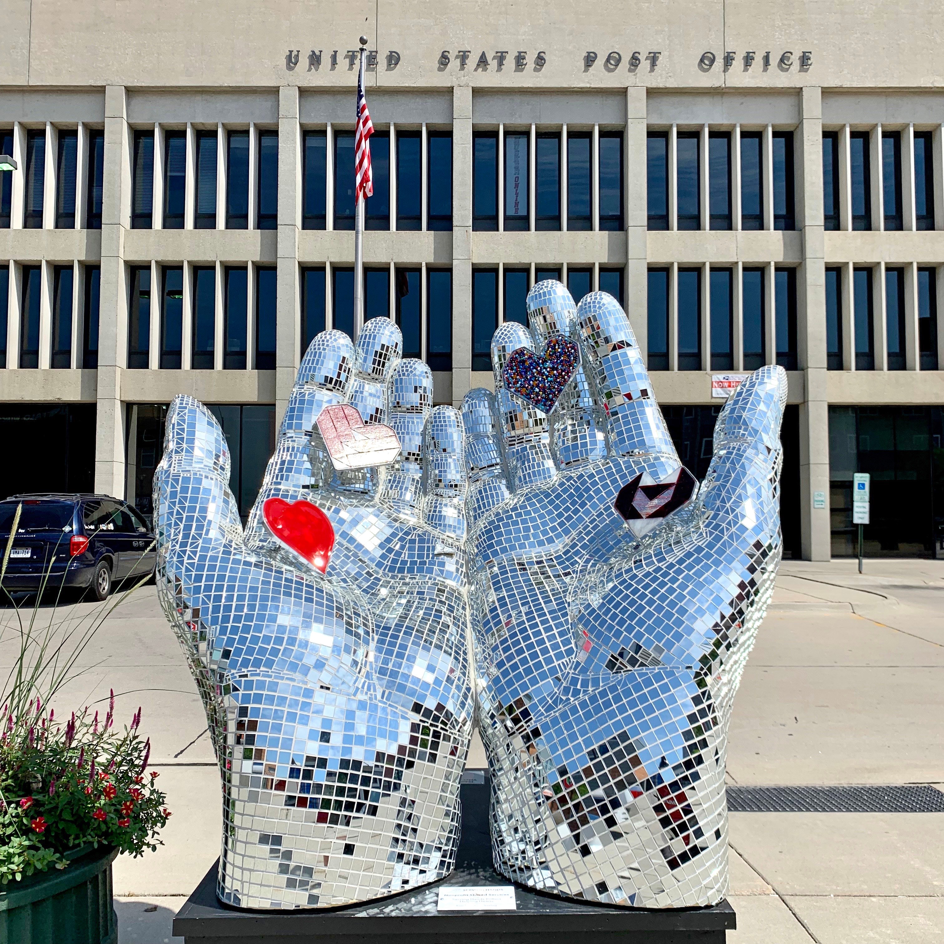 Mirror mosaic hands sculpture holding hearts in front of the US Post Office in Lincoln NE
