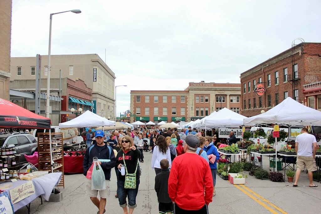 Outdoor farmers market with white tents and crowds in the Haymarket District