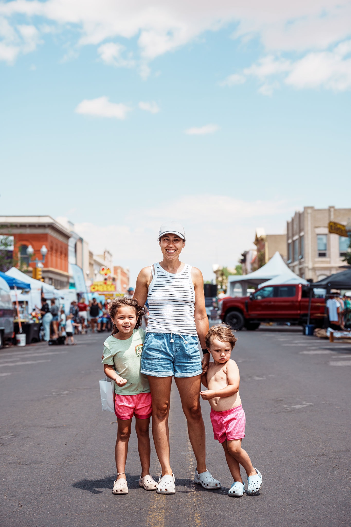 Mom and two young children smiling in the middle of a Haymarket street festival