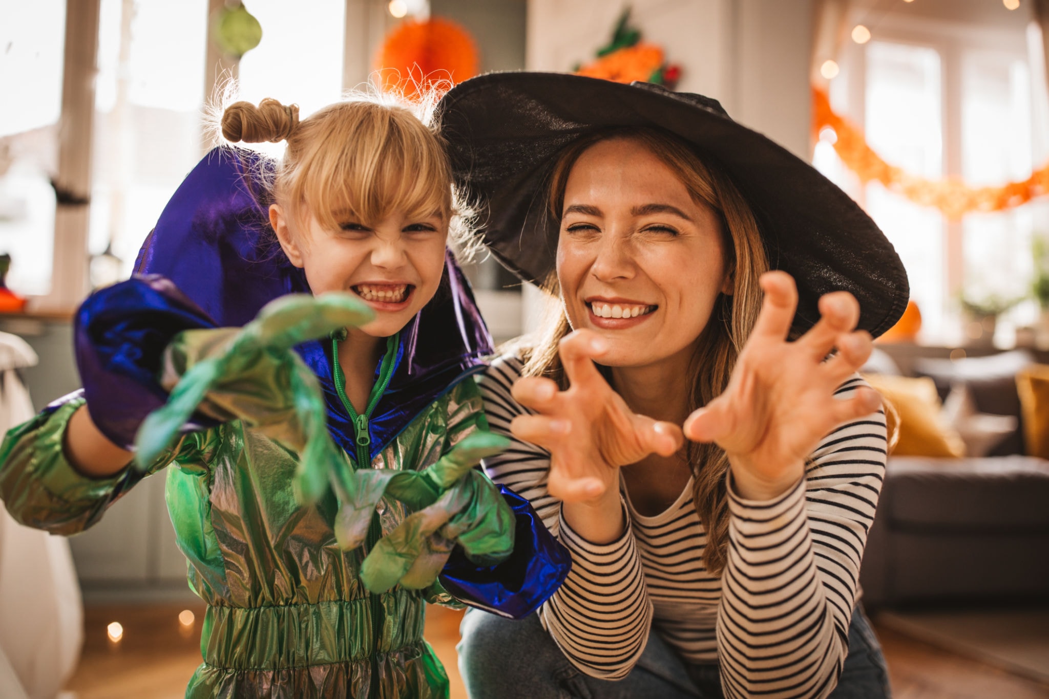 Mom and child in Halloween costumes laughing together at the fall festival