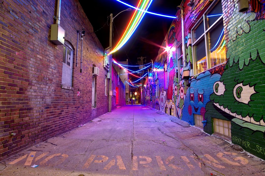 Vibrant neon-lit alley with murals in the Haymarket District at night