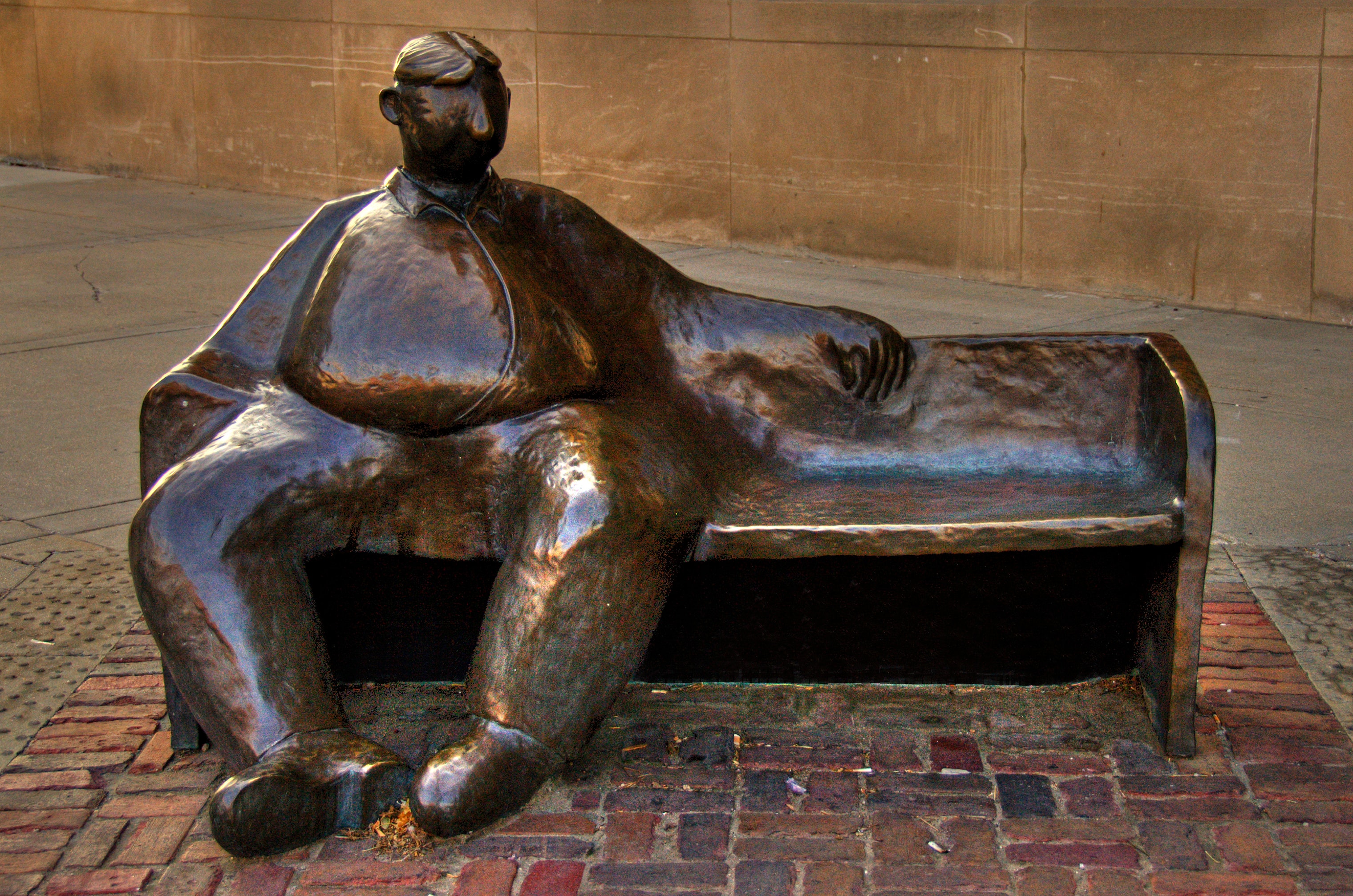 Bronze sculpture of a seated figure on a bench in the Haymarket District